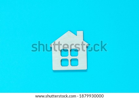 Figurine of a wooden house on a blue background. Concept of real estate, home purchase and sale. Affordable housing at a low price. Home for the family. Stay at home concept.