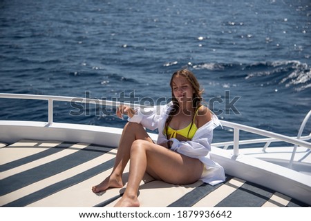 Joyful young woman portrait. Happy teenage girl sitting on deck of sailing yacht, have fun discovering islands in tropical sea on summer coastal cruise. Travel adventure, yachting