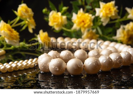 Pearl necklace and bouquet of roses with dew on wet surface, selective focus.