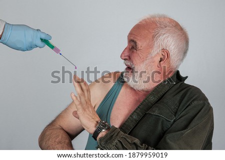 An elderly man is afraid of the corona vaccination and the possible side effects of the immunization. Royalty-Free Stock Photo #1879959019