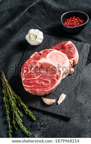 Raw beef ossobuco on a table with spices. Black background. Top view