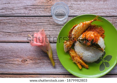 A picture of Ikan Kembung  "asam pedas" with white rice on a wooden background. "Asam pedas" is sour soup made from tamarind, chilli and spices that is popular in Malaysia .