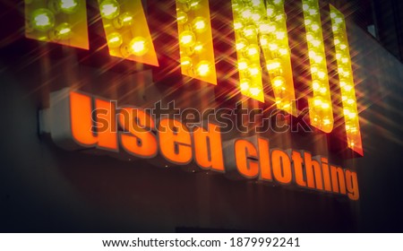 Orange letters saying "used clothing" on a wall of a thrift store