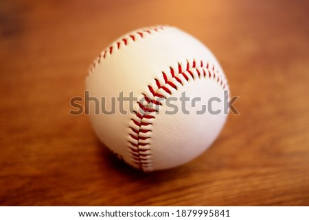 This is a picture of a baseball on a wooden table. It can be used for photo editing and compositing.