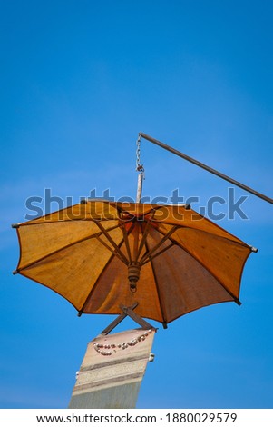 Hanging orange umbrella and native fabric  in the blue sky.