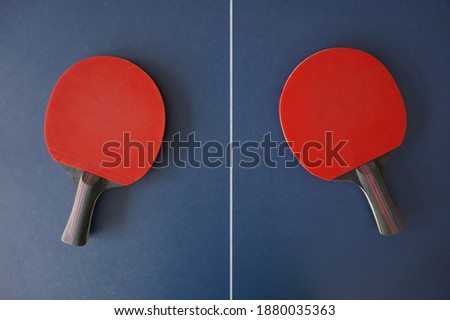 two red ping pong racket or bat on a blue table tennis