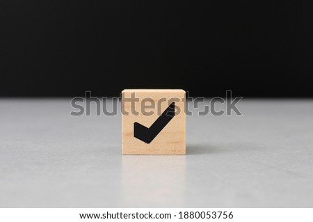 check mark symbol on wooden cube block cement top black background