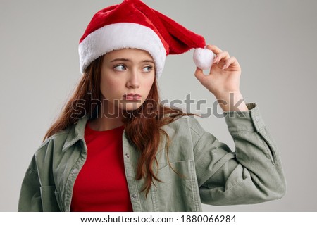 portrait of a girl in a New Year's hat and jacket on a gray background 