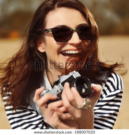 Happy laughing girl with camera on the beach