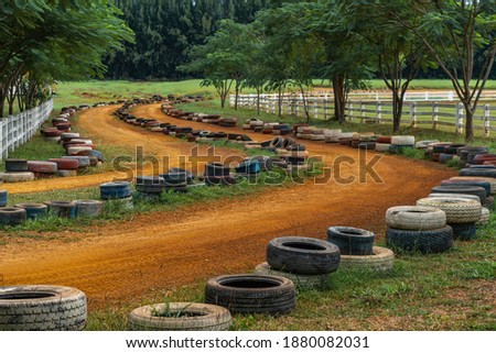 Empty landscape ATV motorcycle road track in farm of Thailand for tourist riding travel in farm, Using the used tires to make the riding boundaries. Background of nature. No people in the image. Royalty-Free Stock Photo #1880082031