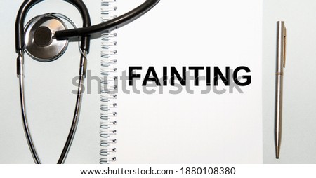 In the notebook is the text of FAINTING, next to the stethoscope and pen.