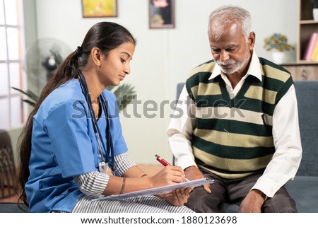 Young doctor or nurse writing prescription during home medical service or visit to senior man