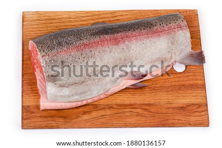 Part of uncooked carcass of a fresh rainbow trout without a head and tail, peeled from fish scales on the wooden cutting board on a white background, top view 
