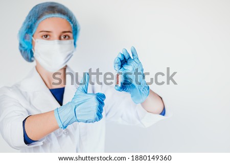 The concept of health care during an epidemic.woman doctor her hold ampoule bottle vaccine fo cus on glass virus label, white background, COVID-19 concept.Vaccination.