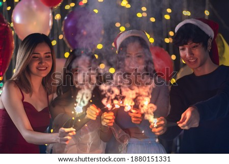 Happy friends celebrating with sparkler fireworks on new year's eve 2021- Different age of people having fun together in patio home party doing selfie - Winter and holidays concept
