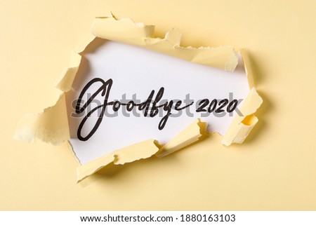 Phrase Goodbye 2020 on white background, view through torn yellow paper Royalty-Free Stock Photo #1880163103