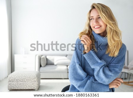 Beautiful young woman wearing warm blue sweater at home. Space for text Royalty-Free Stock Photo #1880163361