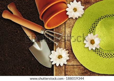 Gardening tools, chamomile and soil on vintage wooden table.
