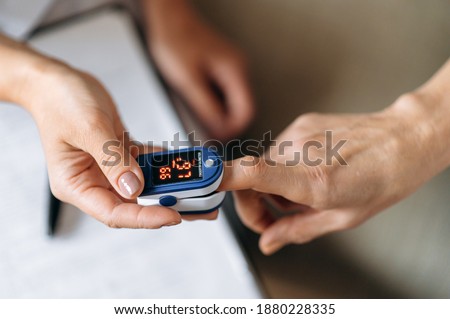 Close-up photo of a female hands. Woman doctor  measures the patient's pulse and oxygen saturation to middle aged woman using a pulse oximeter, healthcare concept
 Royalty-Free Stock Photo #1880228335
