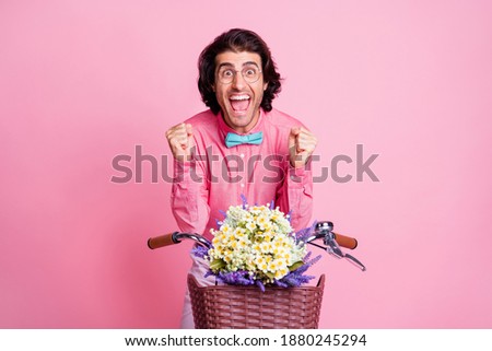 Photo of impressed handsome brunet hair man spectacles sitting bike arms hands fists isolated pink color background