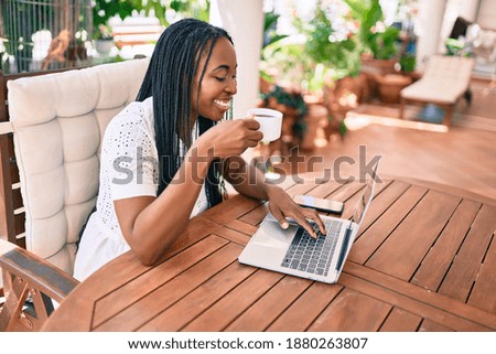 Young african american woman smiling happy working using laptop  and drinking coffee at terrace