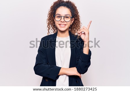 Beautiful kid girl with curly hair wearing business clothes and glasses smiling happy pointing with hand and finger to the side 