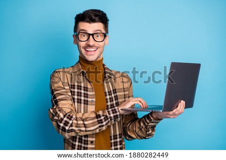 Photo of young handsome attractive excited cheerful positive smiling man working in laptop isolated on blue color background