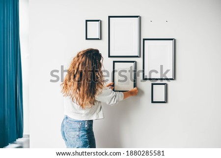 Woman hanging a frame on a wall.