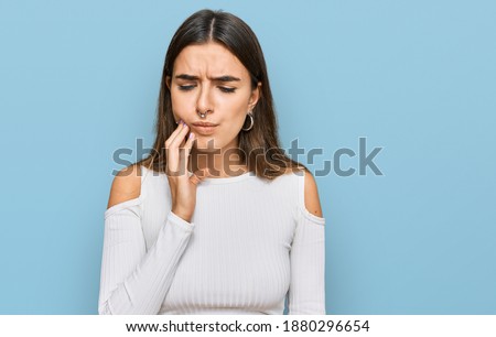 Young hispanic woman wearing casual clothes touching mouth with hand with painful expression because of toothache or dental illness on teeth. dentist 