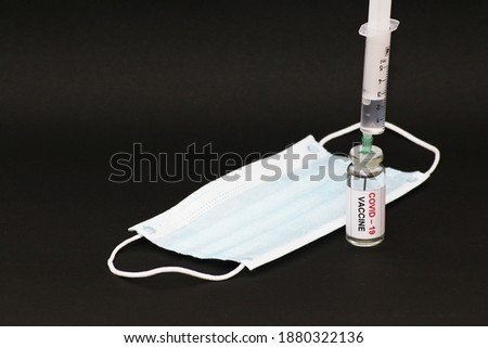 The concept of combating the coronavirus Covid-19. On a black background, a jar with a vaccine and a syringe. Concept: disease, medicine, science.