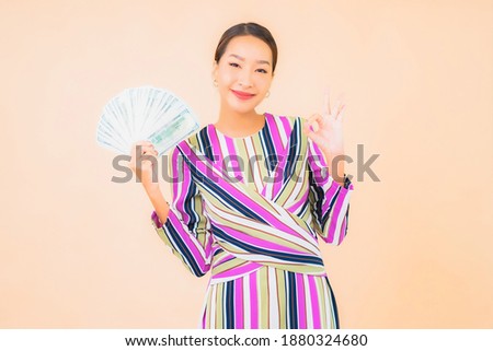 Portrait beautiful young asian woman with cash or money and mobile smart phone on color isolated background