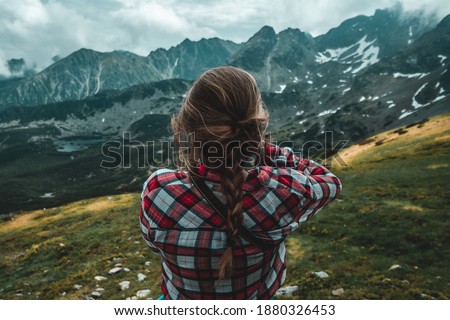 Woman taking a picture of Tatras after a route from Zakopane on a cloudy day when a storm came. Blonde photographer in the Tatras mountains. Mountains of Poland.