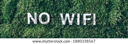 Word WIFI on moss, green grass background. Top view. Copy space. Banner. Biophilia design. Nature backdrop. Mental reset, digital detox. Unplugging, Offline, mindfulness concept.