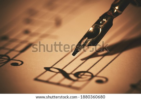 writing musical notes on sheet with quill pen and ink. music education. closeup Royalty-Free Stock Photo #1880360680