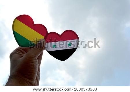 Hand holds a heart Shape Bolivia and Syria flag, love between two countries