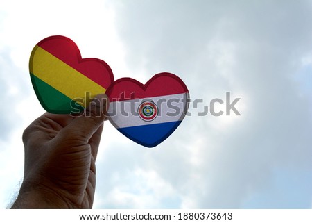 Hand holds a heart Shape Bolivia and Paraguay flag, love between two countries