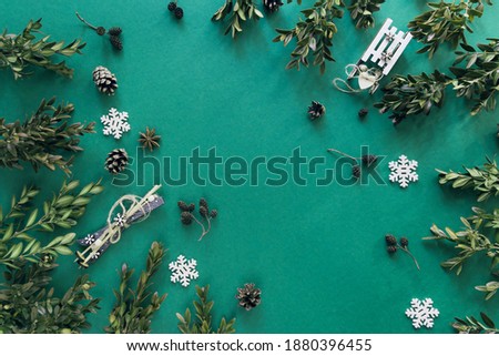 Winter backdrop with boxwood branches, decorative sledge and ski on green background. Top view. Flat lay