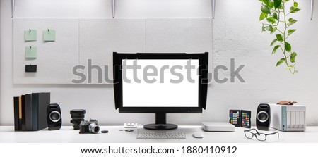 Stylish workspace for photographer with cameras, lens and with computer screen with copy space on long desk