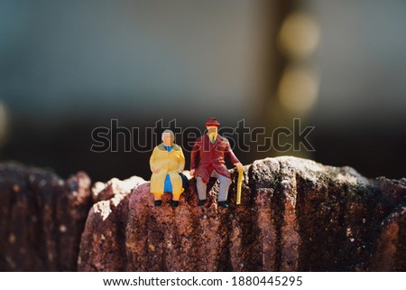 Miniature people, elderly people sitting on blurry background using as job retirement and insurance concept
