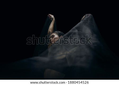 Falling. Graceful classic female ballet dancer isolated on black studio background. Woman in minimalistic black cloth looks graceful, inspired. The grace, artist, movement, action and motion concept.