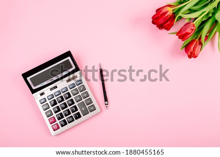 Bouquet of red tulips on pink paper background with calculator and pen are a template for advertising or visualization of blog with copy space for text. Business holiday card. Certificate mockup.