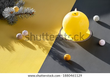 Illuminating Yellow and Ultimate Gray, colors of the year 2021. Fir twigs, burning candle and cotton balls on split yellow grey paper on table Sunlight, long shadows, isometric projection
