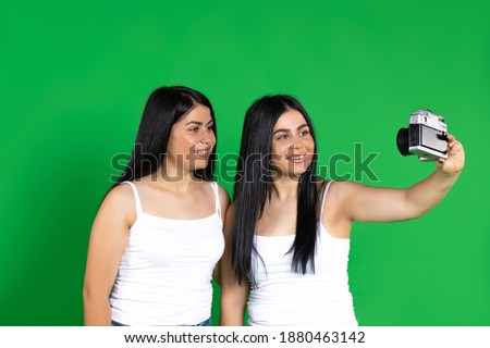 Vintage camera. Twin girls smile and take pictures. Photo on a green background.