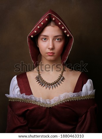 Portrait of a gorgeous girl in medieval time dress and headdress. Royalty-Free Stock Photo #1880463310