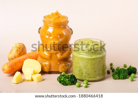 Natural baby food on the wooden background with copy space: jars with vegetable and fruit puree and juice near corn, potato, apples, broccoli, cauliflower, green pea, carrot and pumpkin