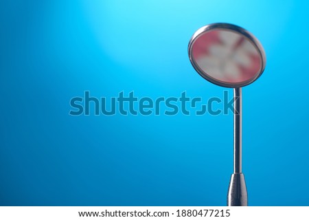 Dental mirror on blue background, close up
