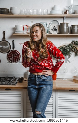 Beautiful blonde girl sitting in New Year's outfit in the kitchen