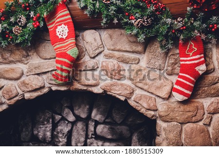 Christmas stockings hanging over a fireplace with candles on the mantlepiece.