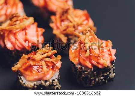 Maki Sushi Rolls with salmon on black stone on dark background. With ginger and wasabi. Sushi menu. Japanese food. Closeup of delicious japanese food with sushi roll. Horizontal photo.