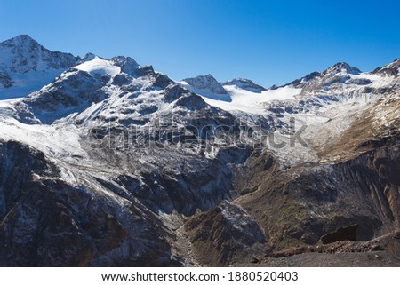 Snow-capped peaks and clear blue skies. Winter mountains, alpine skiing. Sunny snowy landscape. Panoramic mountain view. Rocks and white slopes covered with glaciers